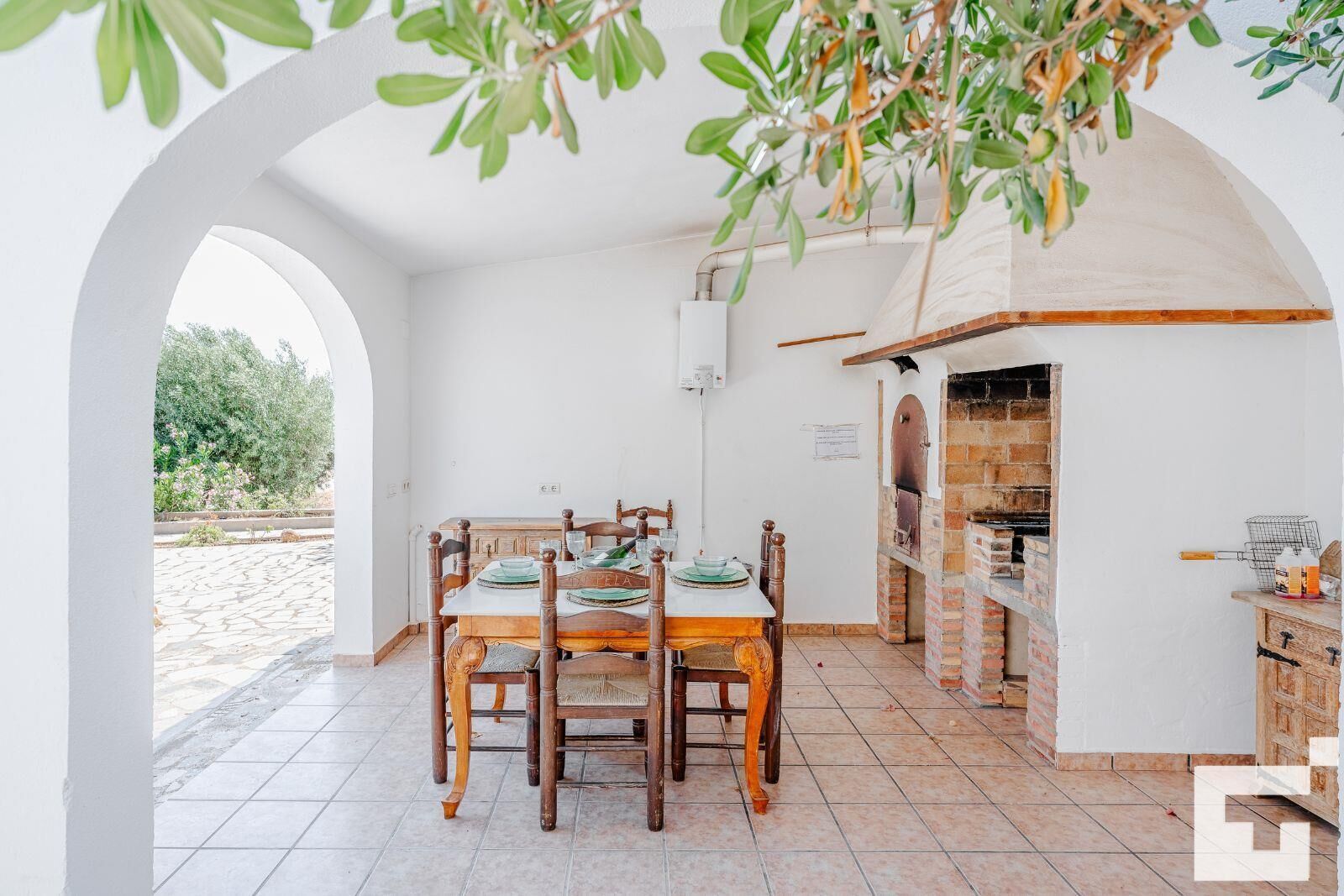 A dining area with a brick oven, white walls, and a view of the outdoors.