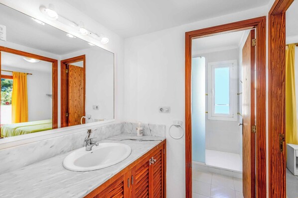 Een moderne badkamer met een marmeren wastafel, houten kastjes en een grote spiegel.