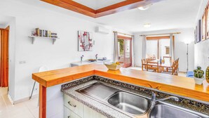 A modern kitchen with a wooden countertop, stainless steel sink, and a dining area with a table and chairs. - Villa Pou Uno - Five Bedroom Villa, Sleeps 10 (Cala d'Or)