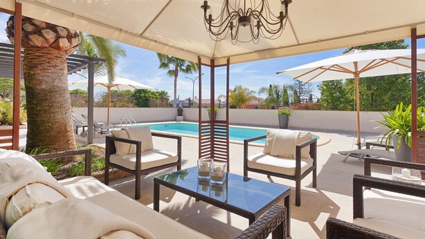 A covered outdoor seating area with wicker furniture, a glass table, and a pool in the background. - GUESTHOUSE PALMA - ADULTS ONLY (Palma de Mallorca)