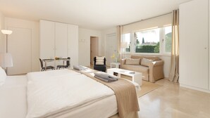 A modern hotel room with a large bed, a desk, a sofa, and a window with curtains. - GUESTHOUSE PALMA - ADULTS ONLY (Palma de Mallorca)