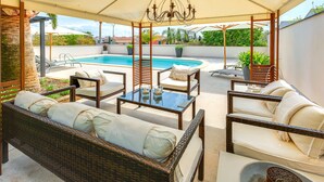 A covered outdoor seating area with wicker furniture, a pool, and a view of the surrounding neighborhood. - GUESTHOUSE PALMA - ADULTS ONLY (Palma de Mallorca)