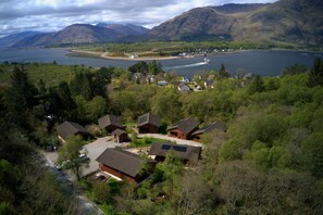 Een groep huizen met een meer en bergen op de achtergrond.