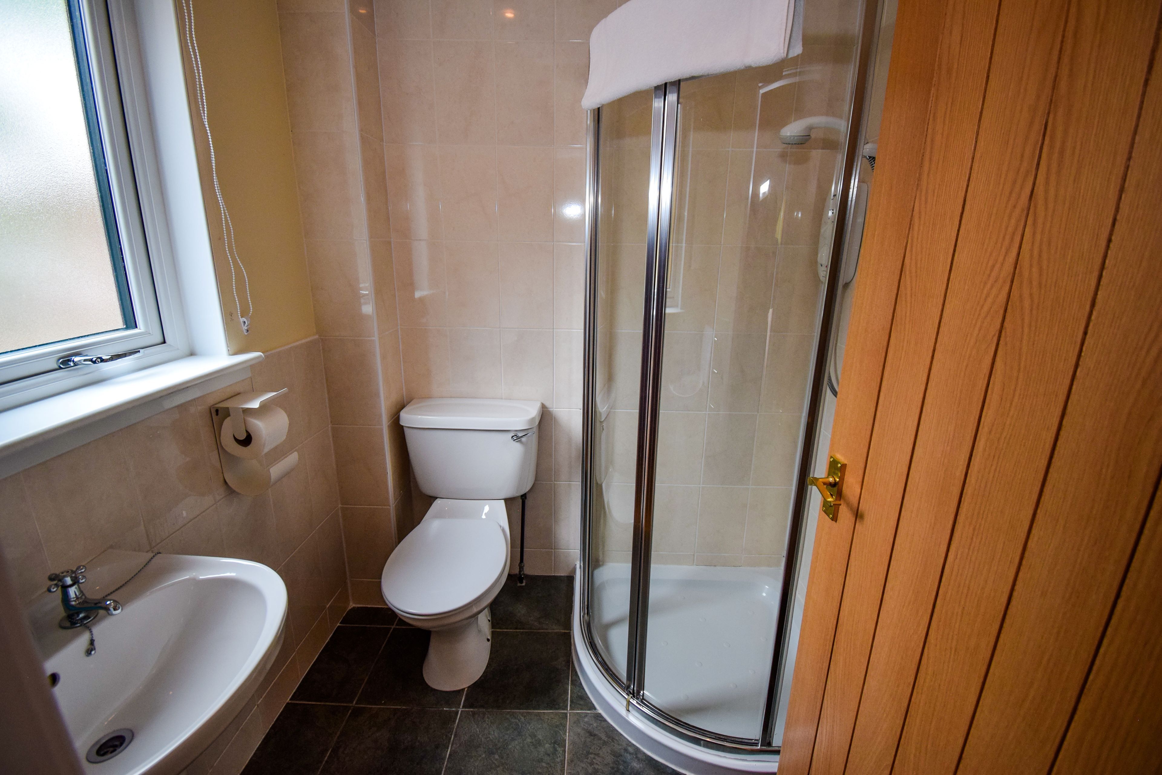 Une salle de bain équipée de toilettes, d’un lavabo et d’une douche à parois en verre.
