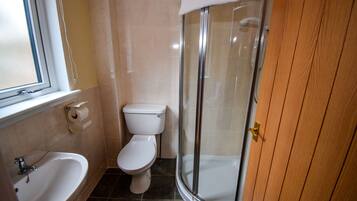 Une salle de bain équipée de toilettes, d’un lavabo et d’une douche à parois en verre.