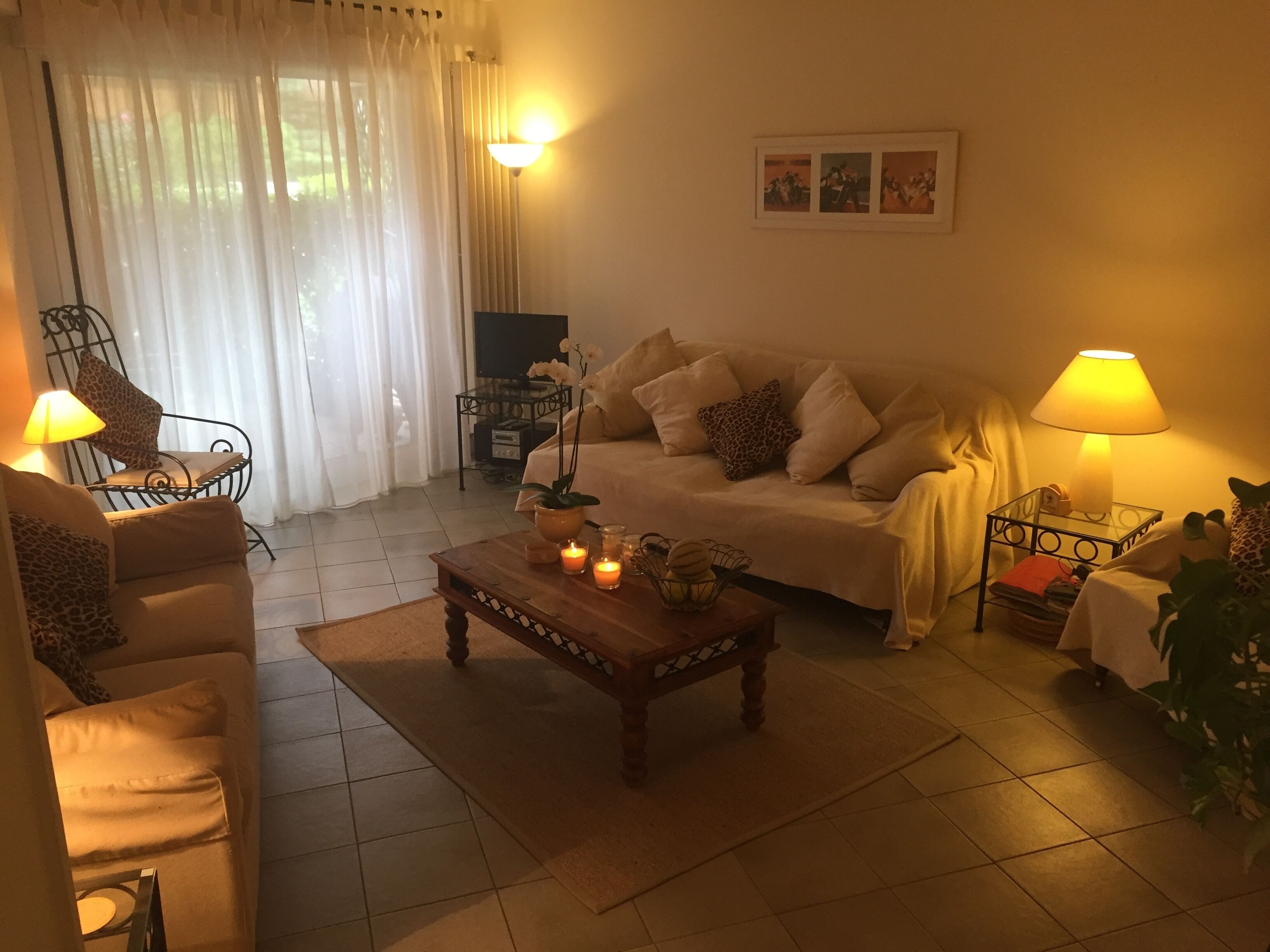 Ein gemütliches Wohnzimmer mit Sofa, Sessel, Couchtisch und Lampen.