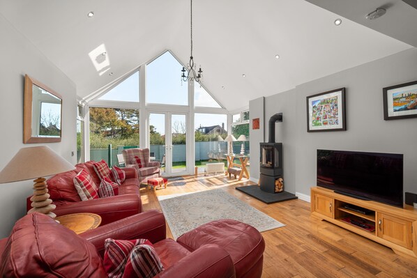 A modern living room with a red leather sofa, a flat-screen TV, and a fireplace.