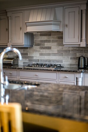 A kitchen with a gas stove, a range hood, and a tiled backsplash. - Modern 2‑Bedroom St Andrews Retreat with Garden, Parking & Easy Walk to Harbour & East Sands (St. Andrews)