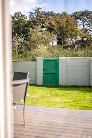A view of a wooden deck with a green gate and a chair. - Modern 2‑Bedroom St Andrews Retreat with Garden, Parking & Easy Walk to Harbour & East Sands (St. Andrews)