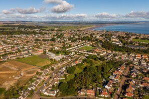 Luchtbeeld van een woongebied met huizen, wegen en een groot wateroppervlak op de achtergrond.