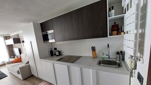Een moderne keuken met witte kastjes, een inbouwoven en een roestvrijstalen spoelbak.