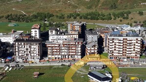 Een hoog hotel met meerdere verdiepingen, een parkeerplaats en uitzicht op het omliggende landschap.