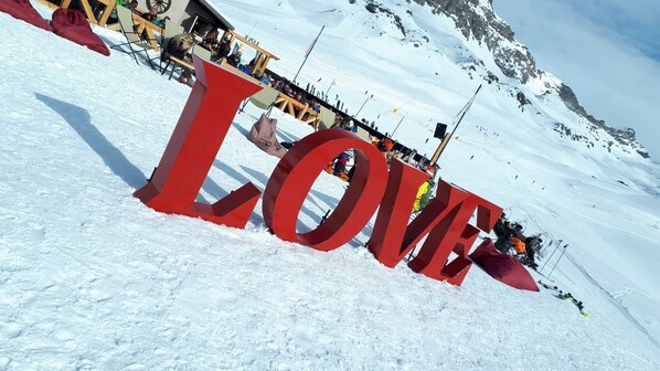 A large red 'LOVE' sign in a snowy landscape with a mountain in the background.
