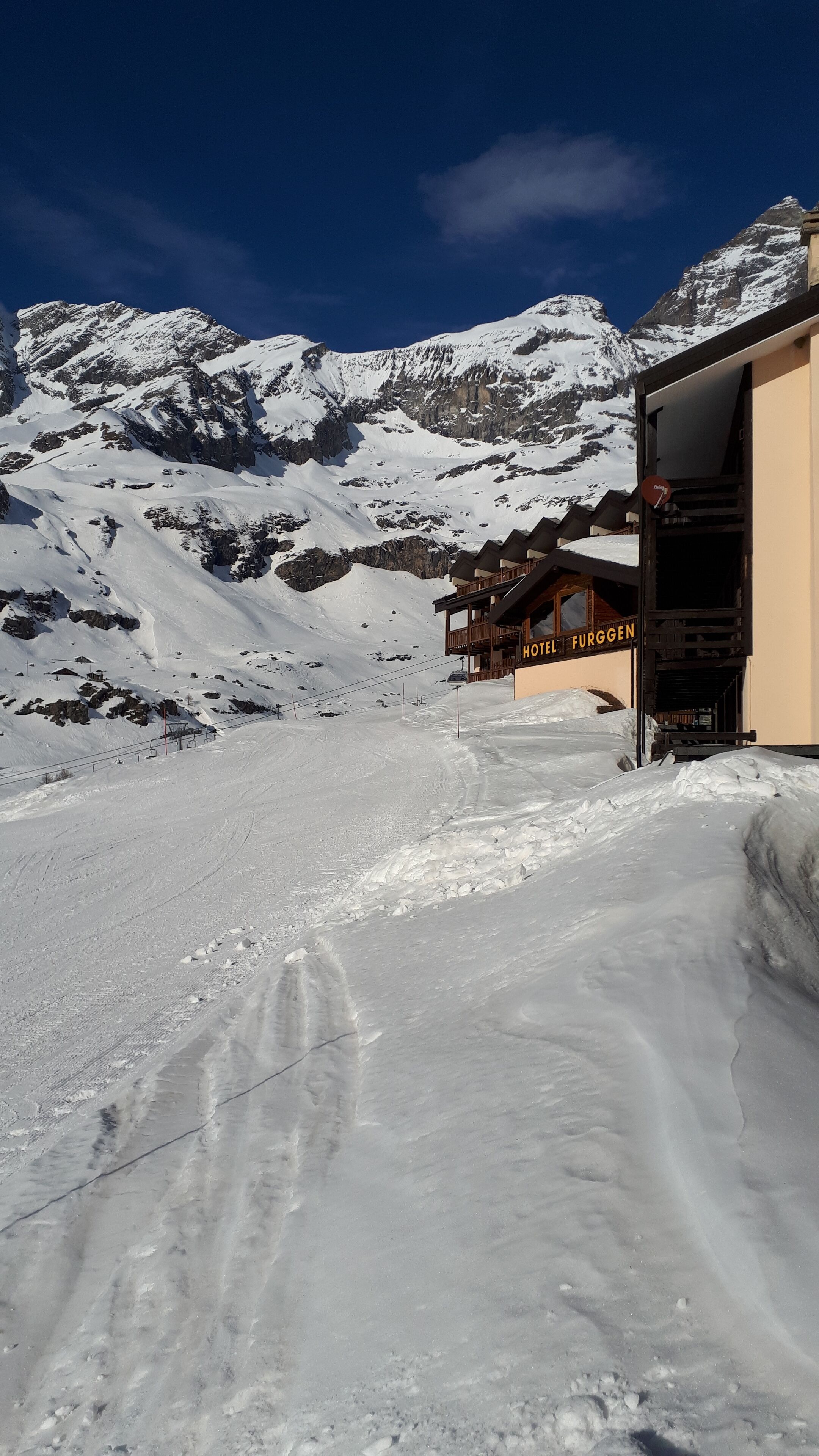 Sendero nevado que conduce a un edificio de madera con la leyenda 'HOTEL FURGEN'.