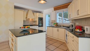 A modern kitchen with white cabinets, a central island, and a stone wall.