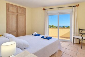 A hotel room with a bed, a chair, a balcony with a view, and a wardrobe.
