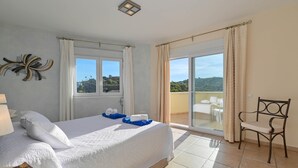 A hotel room with a bed, a chair, a window, and a view of the outdoors.
