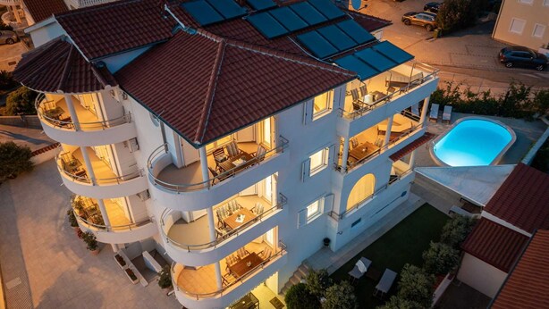 Un edificio de varios pisos con balcones, piscina y terraza en la azotea.