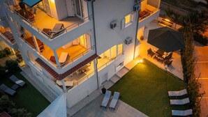 Un edificio de varios pisos con piscina, mobiliario exterior y un patio bien iluminado.