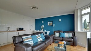 Ein modernes Wohnzimmer mit einem braunen Ledersofa, einem Glastisch und einer blauen Akzentwand.