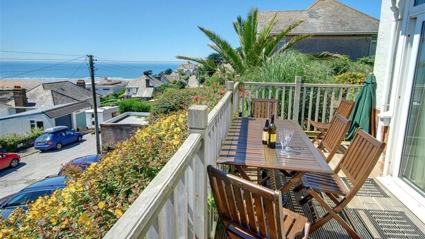 Ein Balkon mit Tisch, Stühlen und einer Weinflasche.