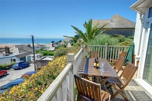 Un balcon avec une table, des chaises et une bouteille de vin.