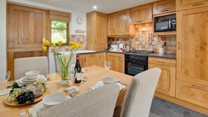 A modern kitchen with wooden cabinets, a dining table set for four, and a breakfast spread.