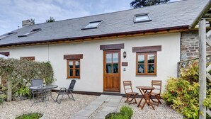A house with a stone exterior, a wooden door, and a small garden with seating.