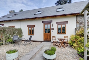 A house with a stone exterior, a wooden door, and a small garden with seating. - 2 Bed in Croyde (oc-longst) (Croyde)