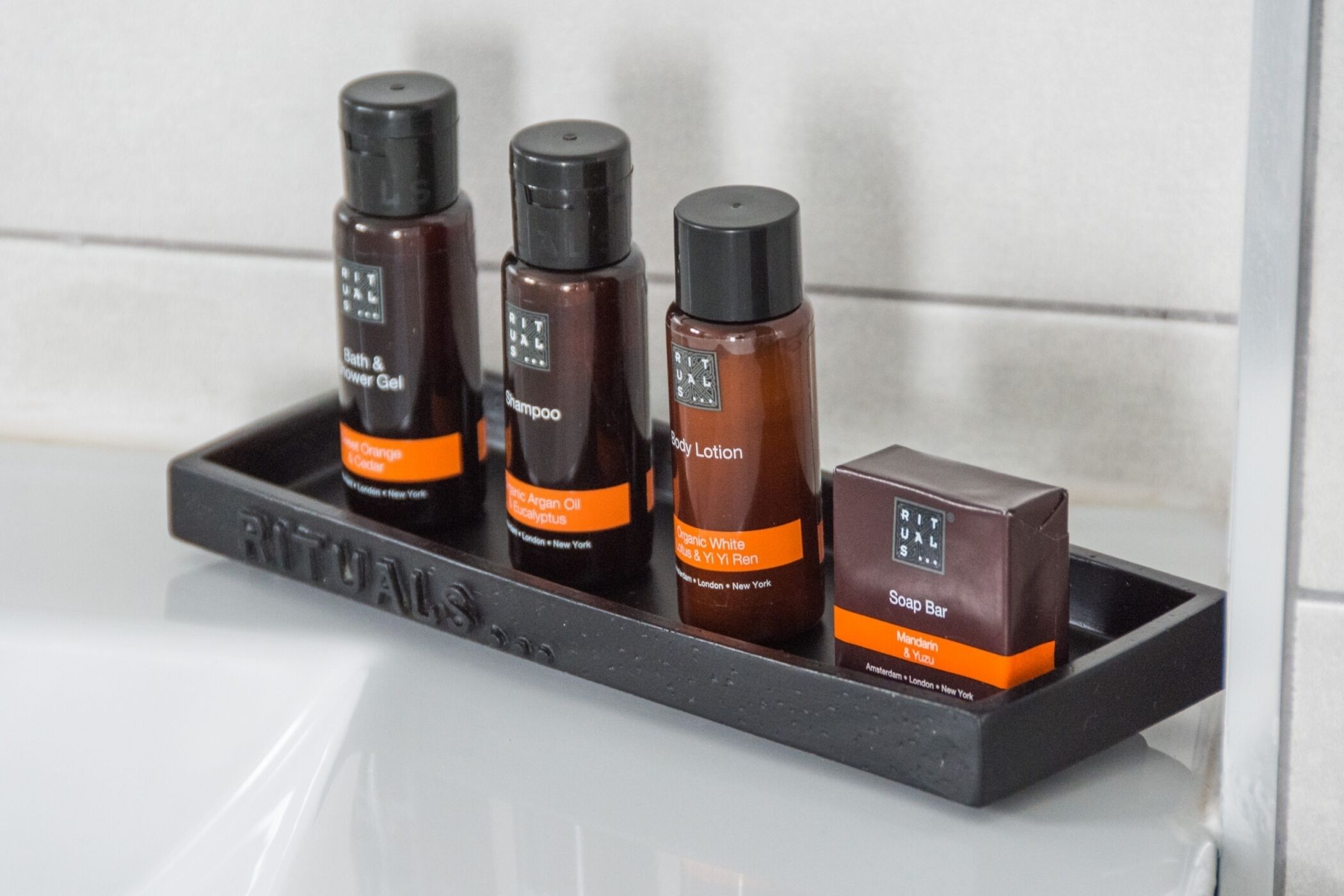 Un estante de baño con cuatro productos de Rituals y una pastilla de jabón.