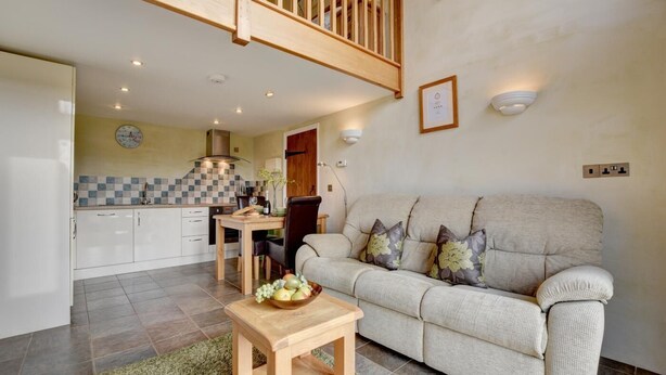A living room with a sofa, a small wooden table, and a kitchen in the background.
