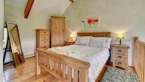 A bedroom with a wooden bed, a nightstand, a dresser, and a radiator.