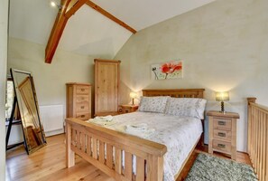 A bedroom with a wooden bed, a nightstand, a dresser, and a radiator.