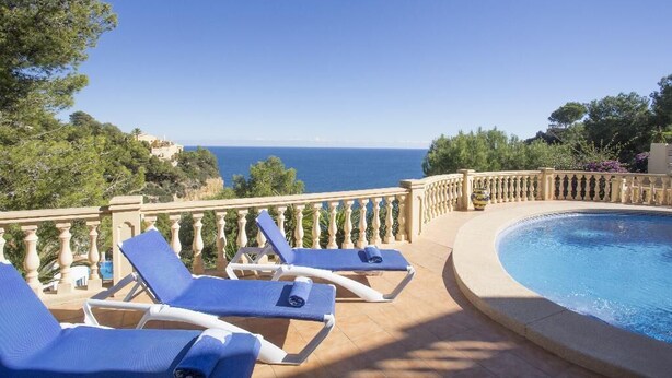 Un espace aménagé au bord de la piscine, avec des chaises longues et une vue sur la mer.