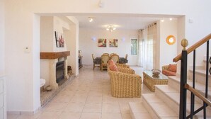 Un salon spacieux avec une cheminée, des meubles en osier et un escalier.