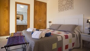 Une chambre à coucher avec un lit, une table de chevet, une lampe, un miroir et une porte.