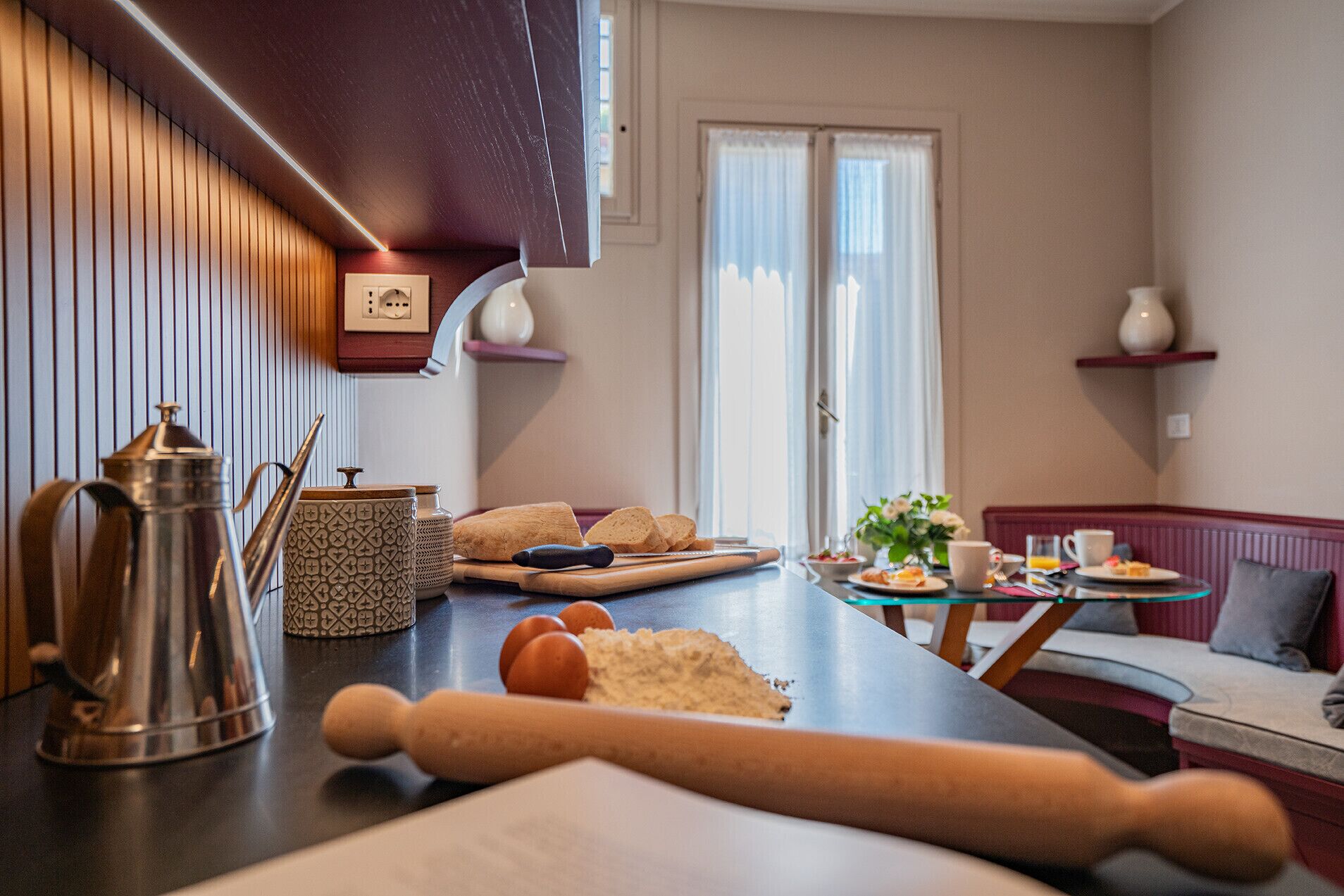 A modern kitchen with a wooden countertop, a rolling pin, a coffee pot, and a cutting board.