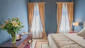 Een slaapkamer met een bed, nachtkastje, lamp en een bloemenvaas.
