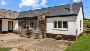 A small, single-story house with a sloped roof and a chimney. - Linhay Cottage, Withypool (Withypool)