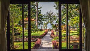 Un sendero que lleva a una edificación tradicional rodeada de exuberante vegetación y vistas al mar.