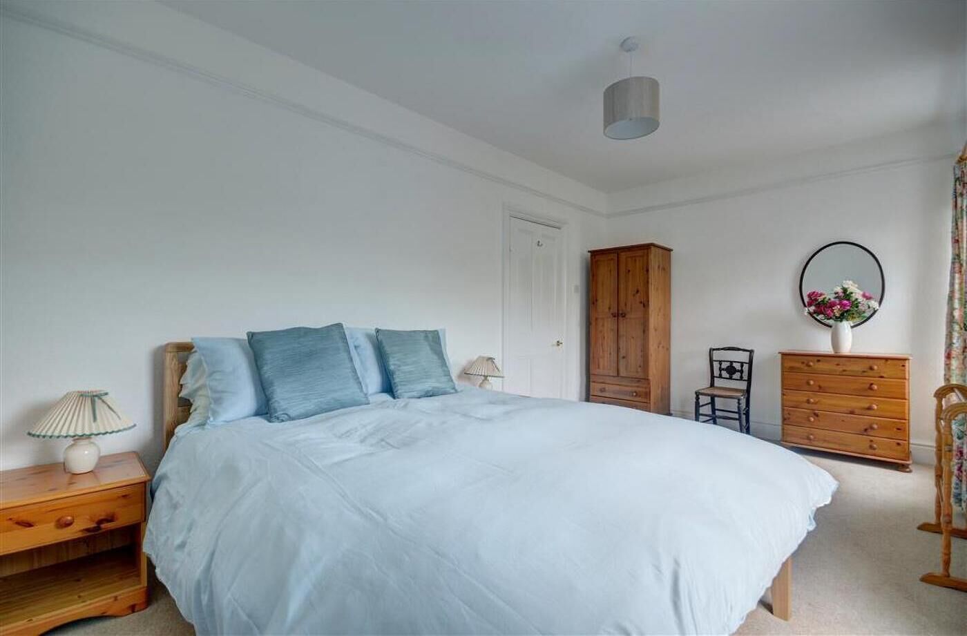 Een slaapkamer met een bed, een nachtkastje van hout, een dressoir en een garderobe.