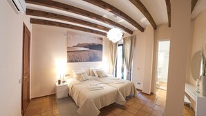 Une chambre avec deux lits, un grand tableau, un lustre et une vue sur la salle de bain.