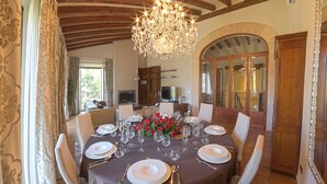 Une salle à manger avec une table ronde dressée pour le repas, entourée de chaises.