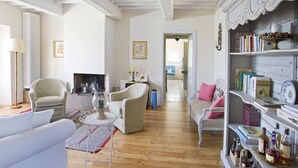 A living room with a fireplace, two armchairs, a sofa, a coffee table, and a bookshelf with books and decorative items. - Breathtaking views of the Chianti hills, Tradition, Sustainability and Design (Montespertoli/Firenze)