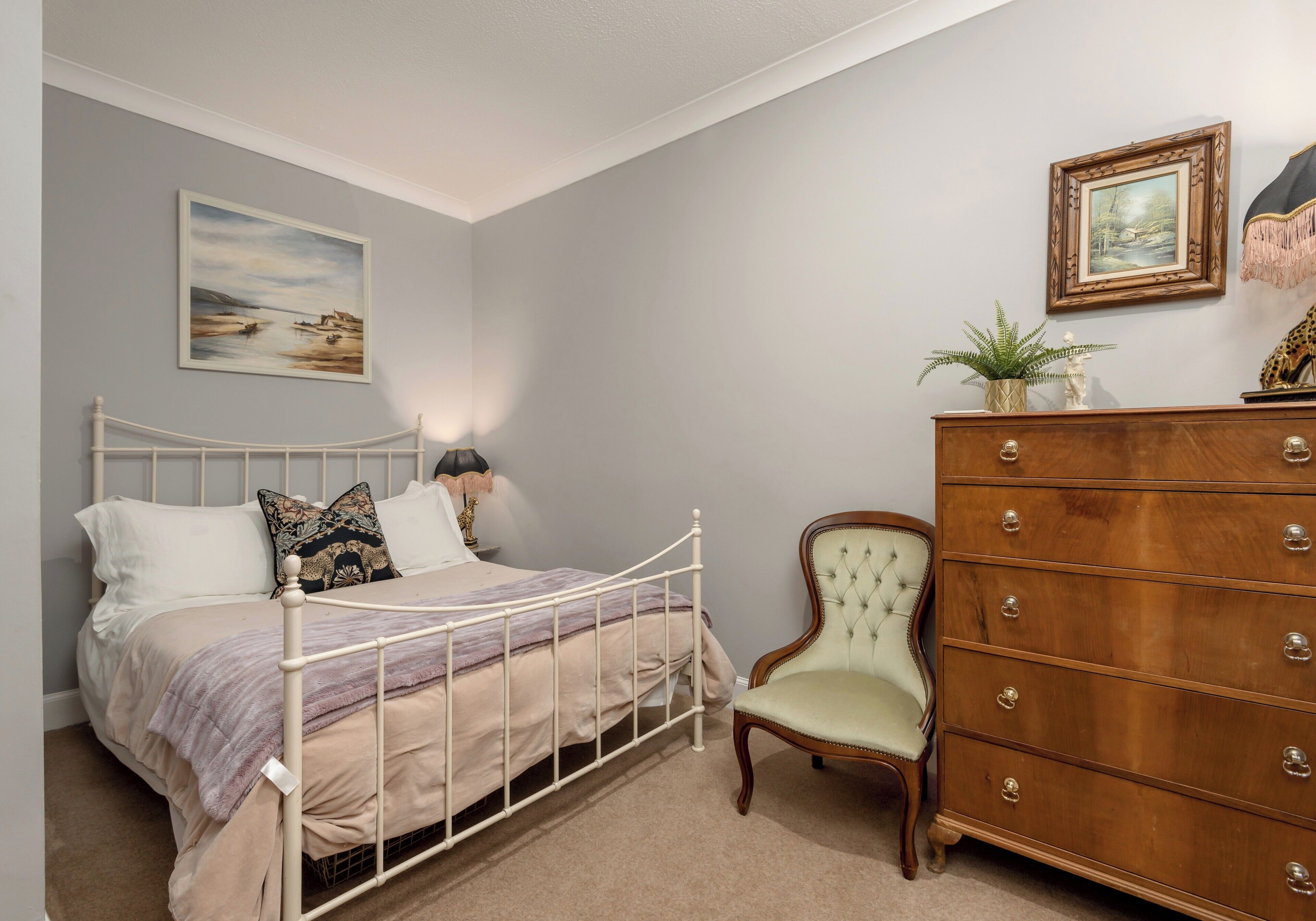 Een slaapkamer met een bed, een dressoir en twee ingelijste foto's aan de muur.