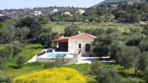 A villa with a swimming pool, surrounded by greenery and hills.