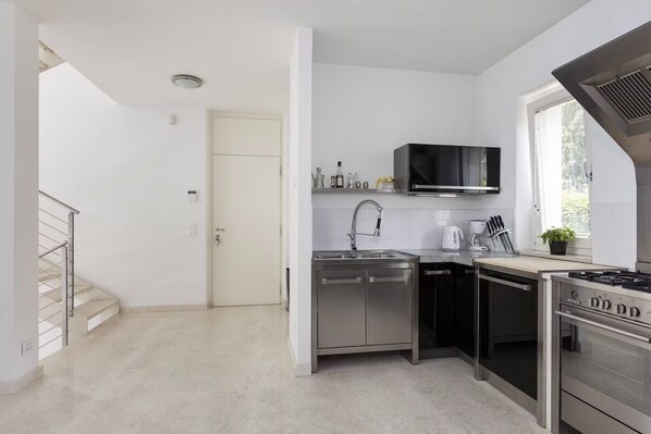 A modern kitchen with stainless steel appliances, a built-in oven, and a window providing natural light.