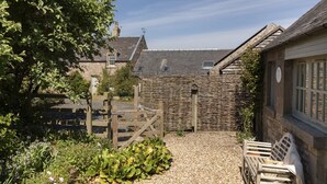 A courtyard with a gravel path, a wooden bench, and a stone wall. - HERITAGE COTTAGE set in peaceful rural surroundings, Scottish Borders (Duns)
