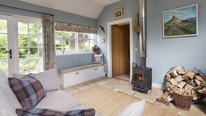 A cozy living room with a sofa, a bench, a fireplace, and a window with curtains. - HERITAGE COTTAGE set in peaceful rural surroundings, Scottish Borders (Duns)
