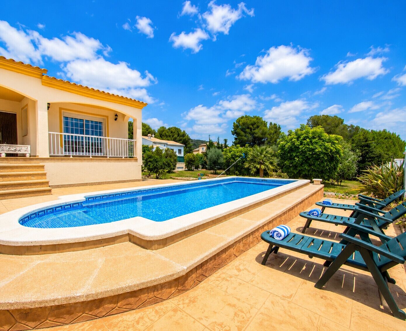 Une piscine dotée d’une terrasse ensoleillée et de chaises longues.